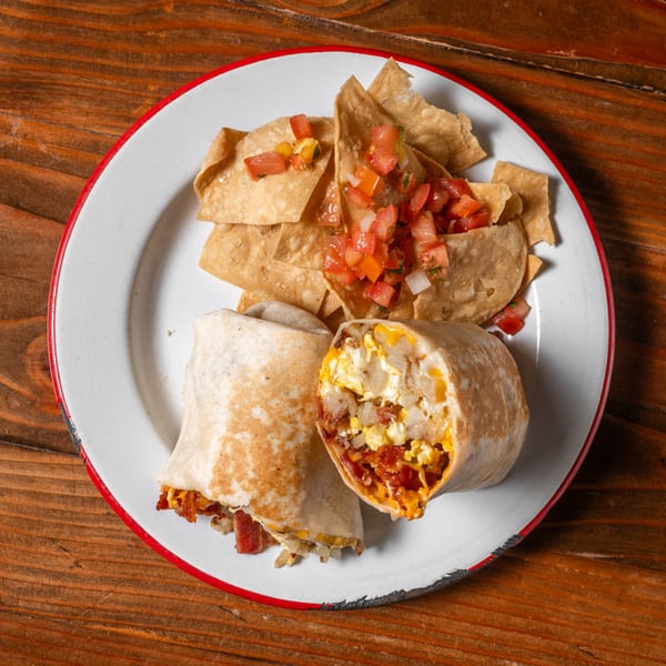 Two breakfast burritos with bacon, eggs, and potatoes, served with tortilla chips and salsa.