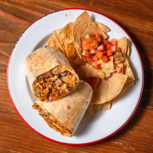 A chorizo and egg breakfast burrito, cut in half, served with tortilla chips and pico de gallo.